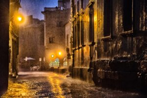 Via del centro storico di Viterbo illuminata dai lampioni sotto la pioggia notturna