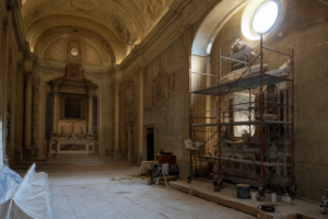 Interno di una chiesa barocca in restauro, con impalcatura attorno a un altare laterale (immagine generata con intelligenza artificiale)