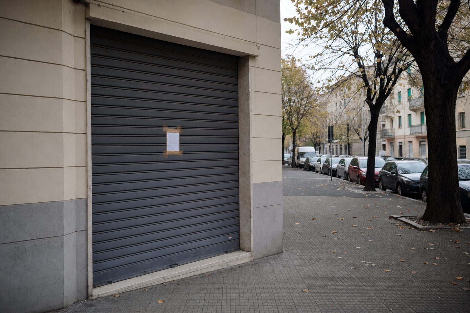 Serranda abbassata di un'attività commerciale su un viale cittadino (immagine generata con intelligenza artificiale)