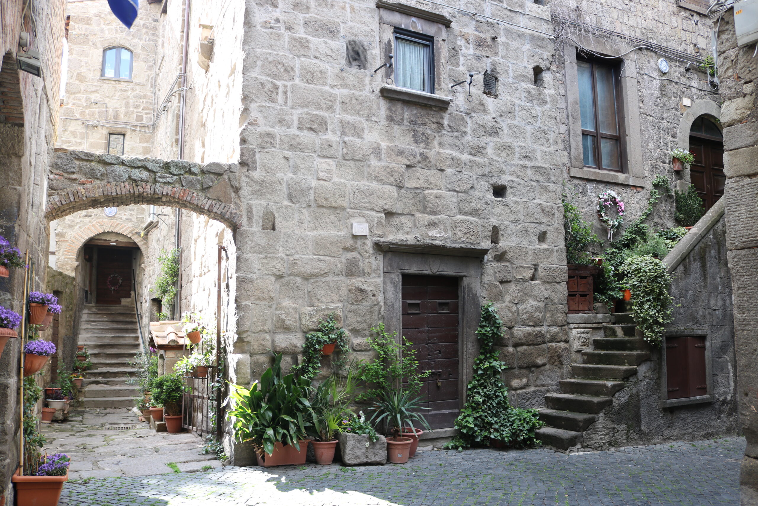 Vicolo in pietra del quartiere San Pellegrino a Viterbo, con piante e fiori