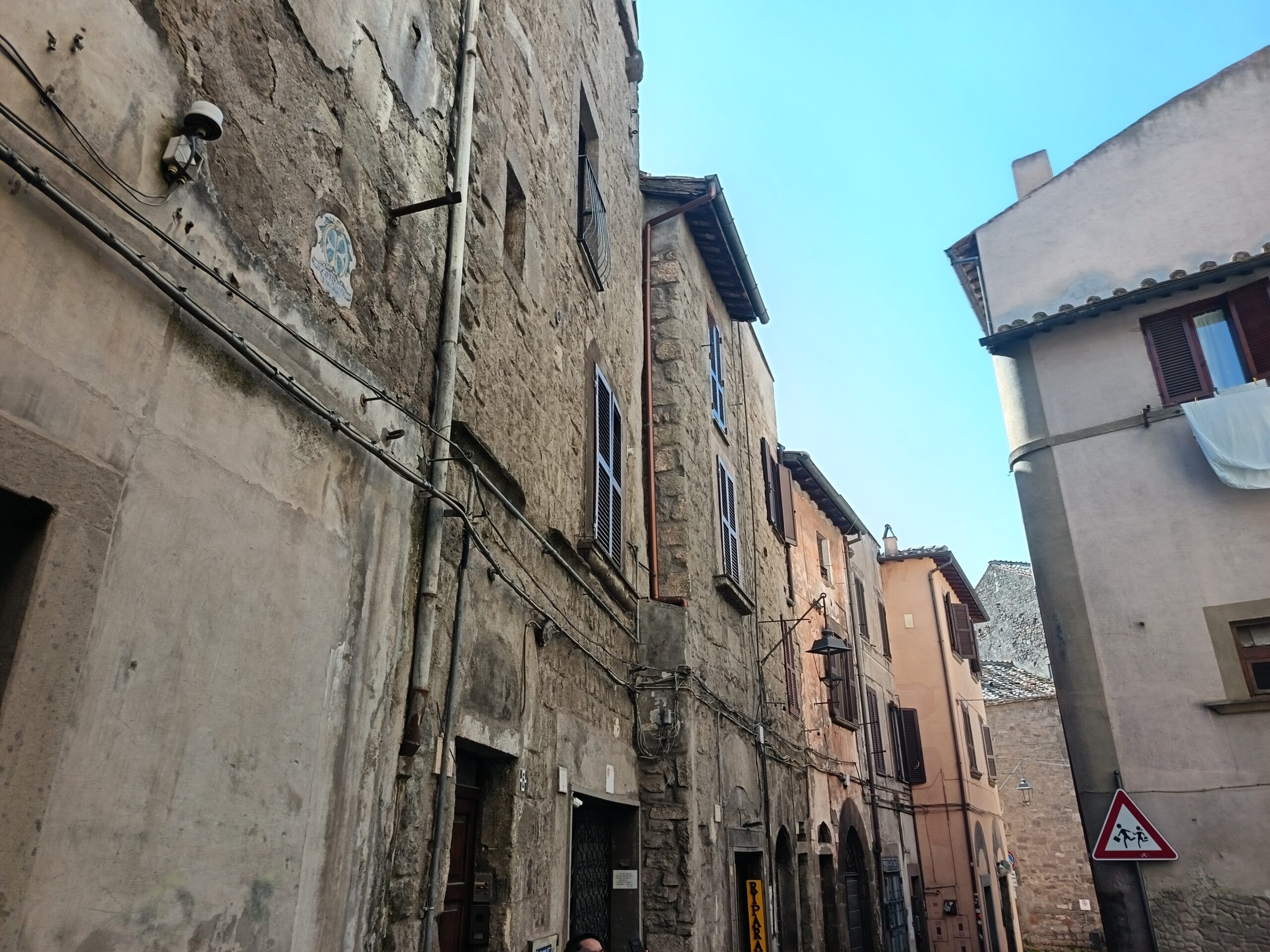 Via del centro storico di Viterbo vista dal basso verso l'alto, tra edifici in pietra