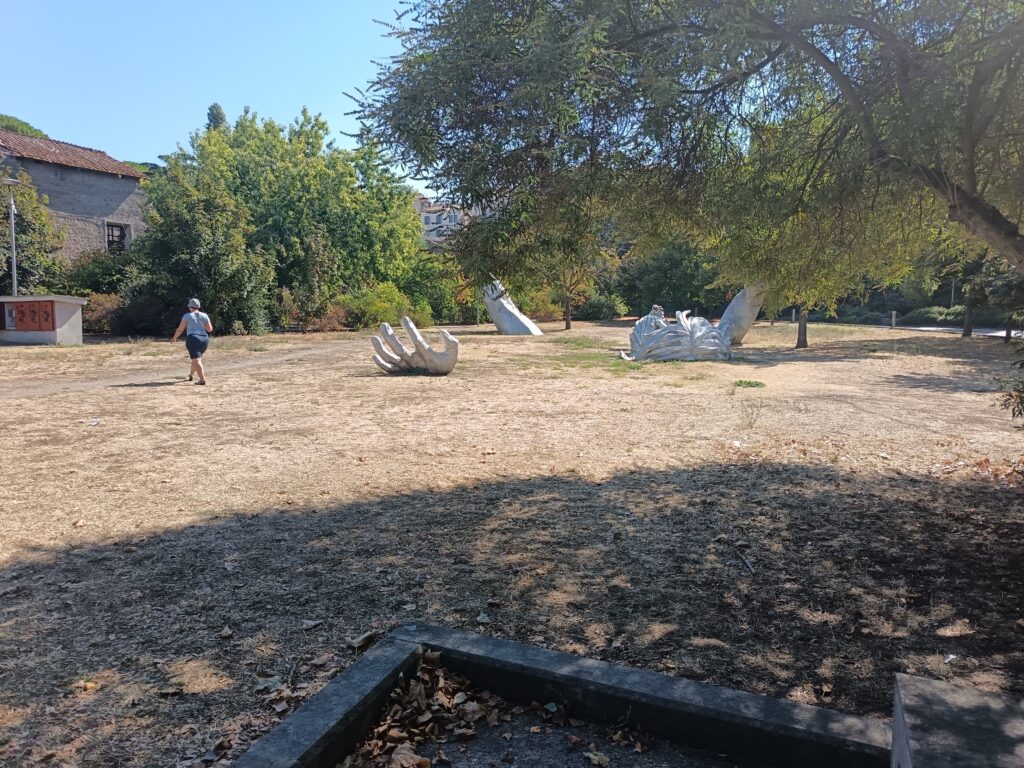 Parco pubblico di Viterbo con grandi sculture moderne e prato completamente inaridito dal caldo estivo
