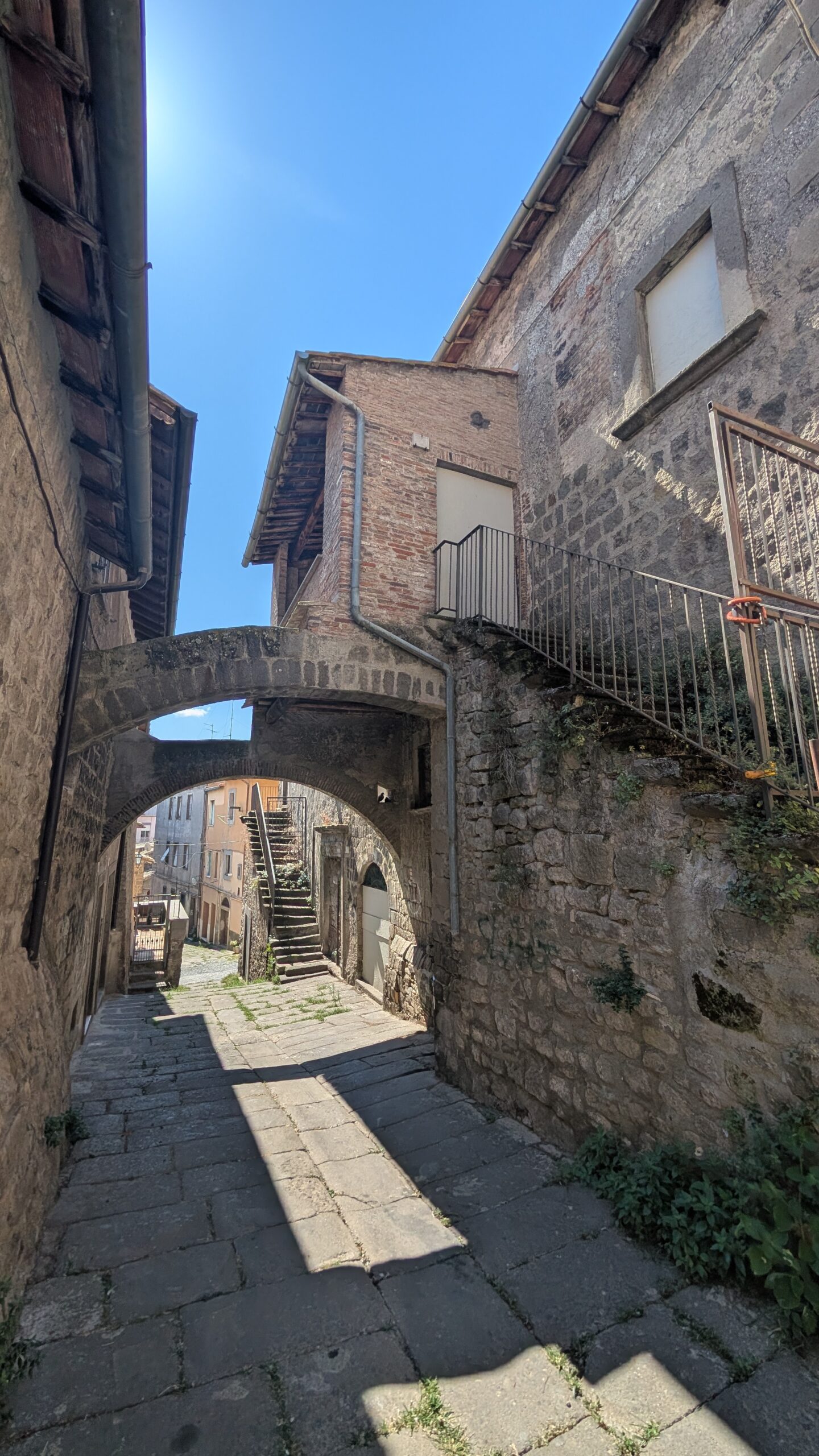 Vicolo medievale con arco e scala esterna in pietra, quartiere San Pellegrino, Viterbo