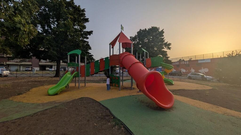 Bambino gioca allo scivolo del parco di via dei Bersaglieri al tramonto