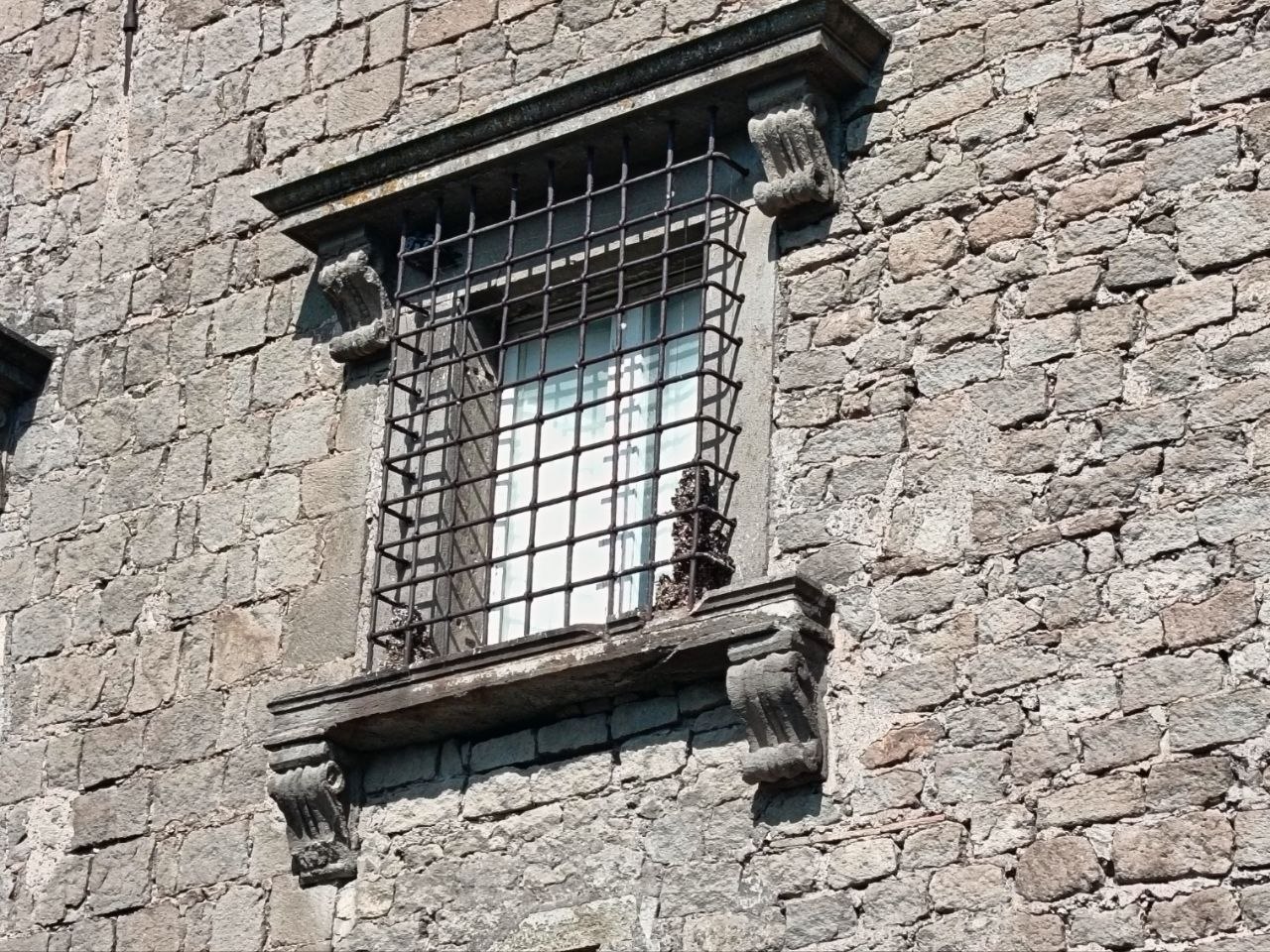 Dettaglio di una finestra del palazzo con l'inferriata originale, vetri intatti ma nessun segno di vita all'interno