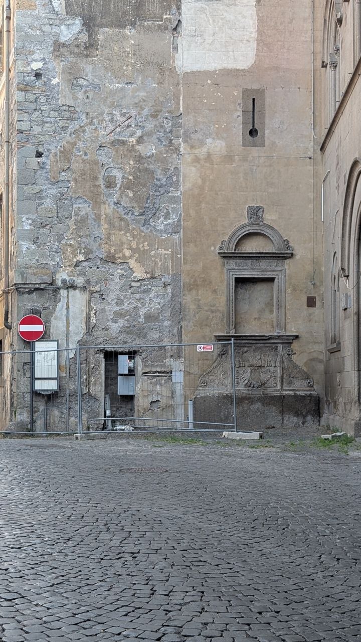 Quel che resta di un'antica fontana nella piazzetta accanto al palazzo, transennata e con la parete scrostata alle spalle