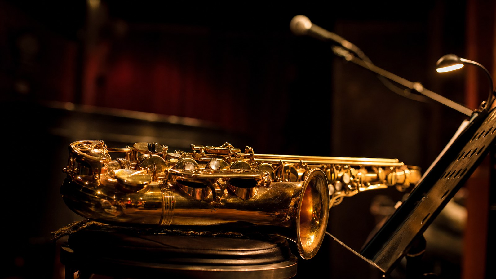 Un sassofono appoggiato su un palco in penombra, senza musicisti