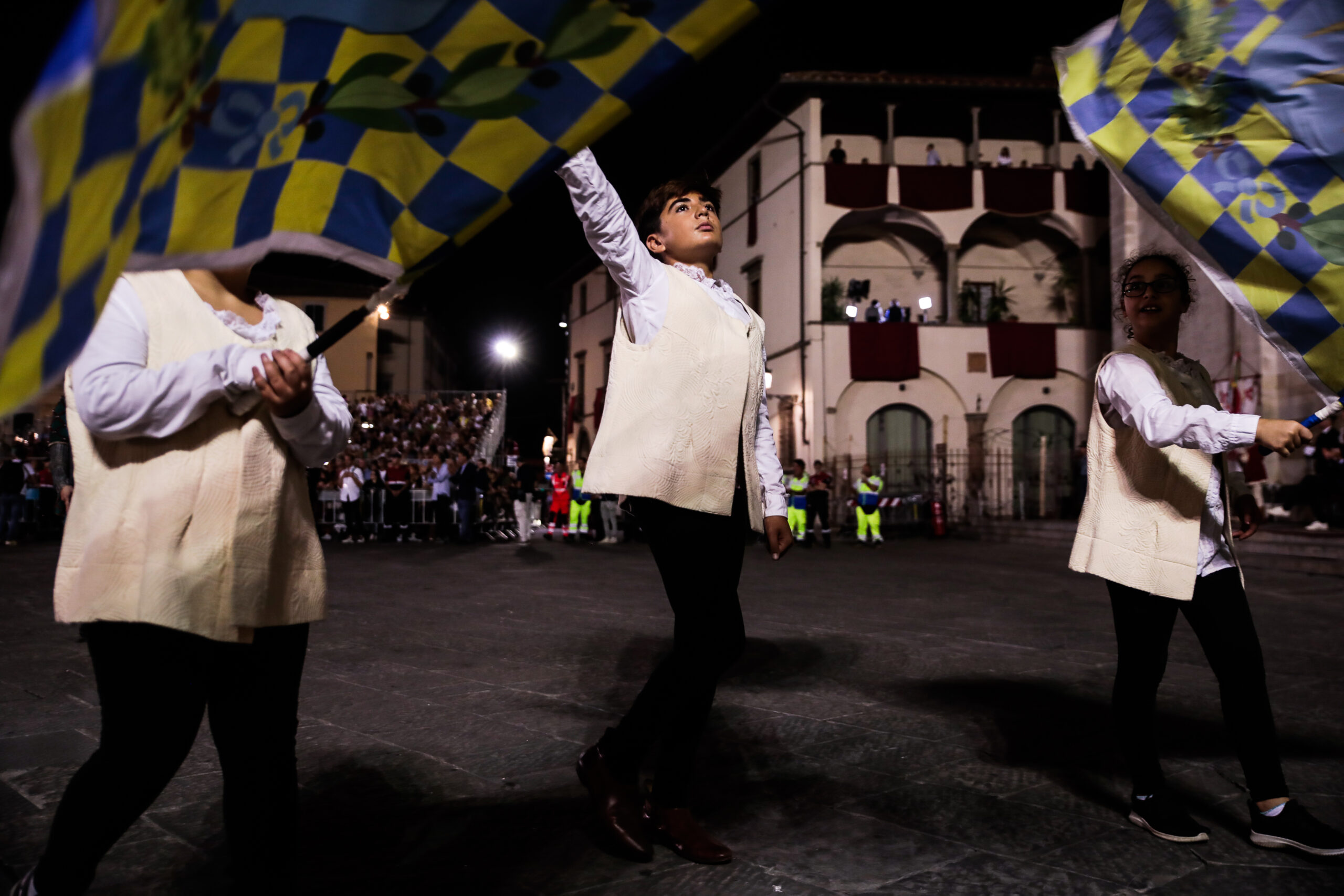 Giovani sbandieratori fanno roteare bandiere colorate durante un corteo storico notturno (foto di repertorio)
