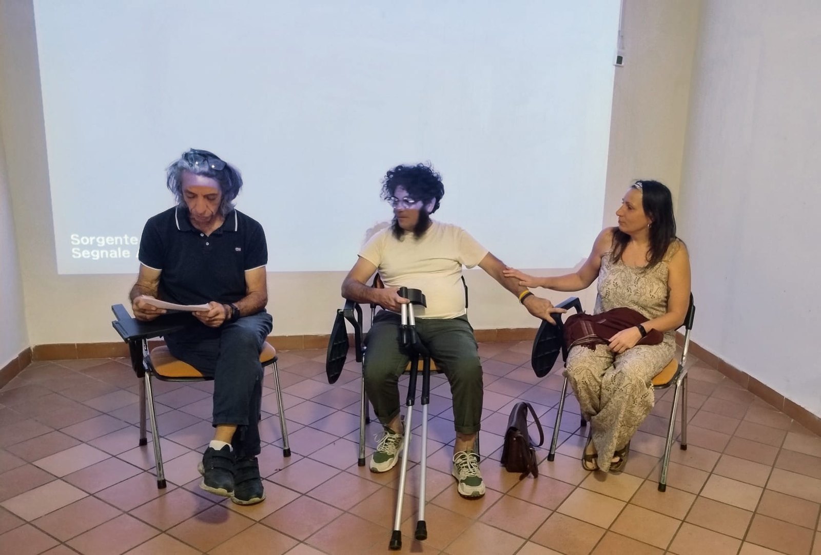 Tre persone sedute davanti a uno schermo durante l'assemblea del Circolo ARCI Il Cantinone a Vignanello