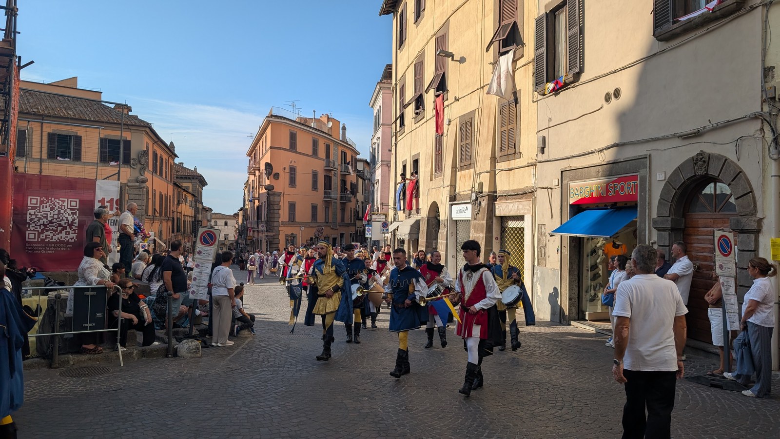 Musici in costume storico con tamburi e chiarine sfilano in via Cavour a Viterbo, con il pubblico ai lati della strada