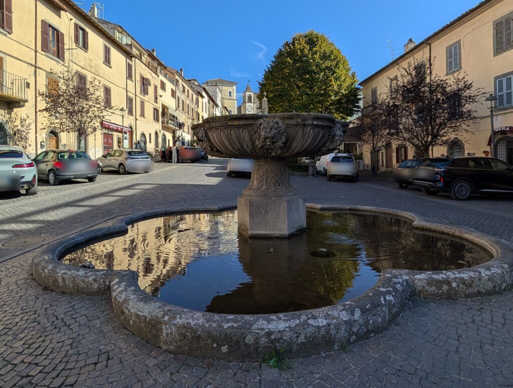 Fontana a coppa con bacino esalobato al centro di piazza Mariano Buratti a San Martino al Cimino, con le auto parcheggiate intorno