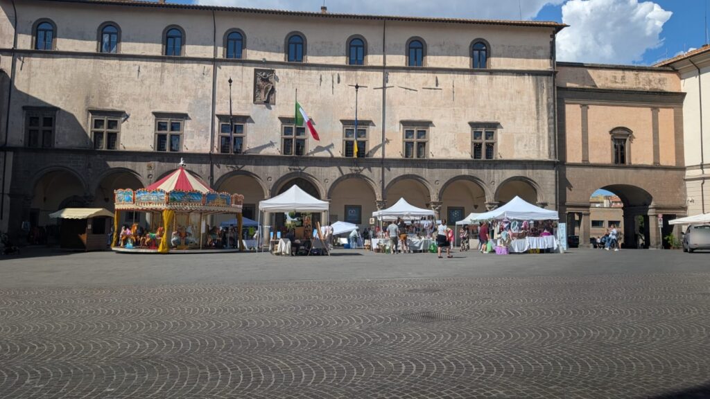 Viterbo Open Mall in piazza del Plebiscito: la giostra e i banchi davanti al Palazzo dei Priori