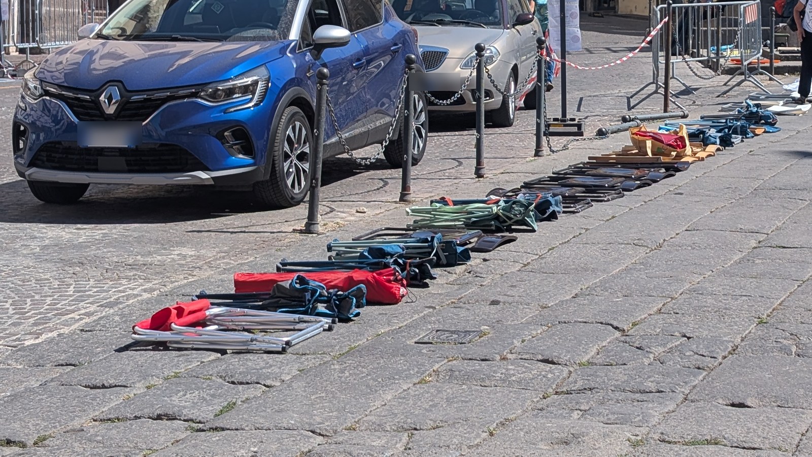 Una fila di sedie pieghevoli appoggiate sul selciato lungo il percorso del Trasporto della Macchina di Santa Rosa, il giorno prima