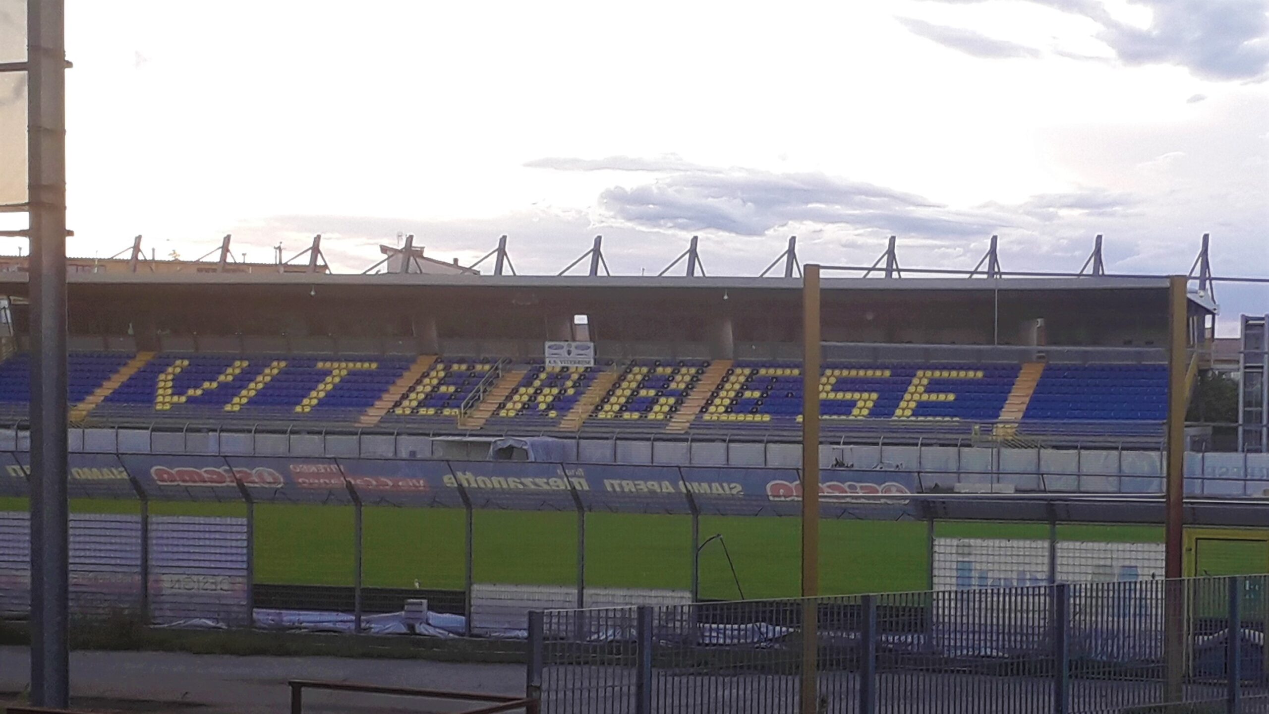La tribuna dello stadio Enrico Rocchi di Viterbo, con i seggiolini gialli e blu che compongono la scritta Viterbese, vista dal campo
