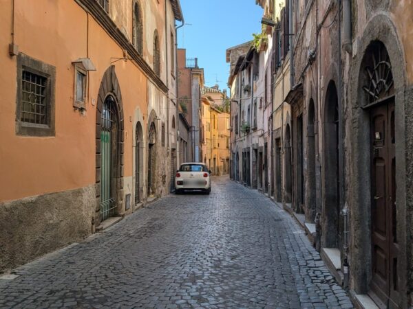 Una via lastricata del centro storico di Viterbo, tra facciate in peperino e portoni ad arco