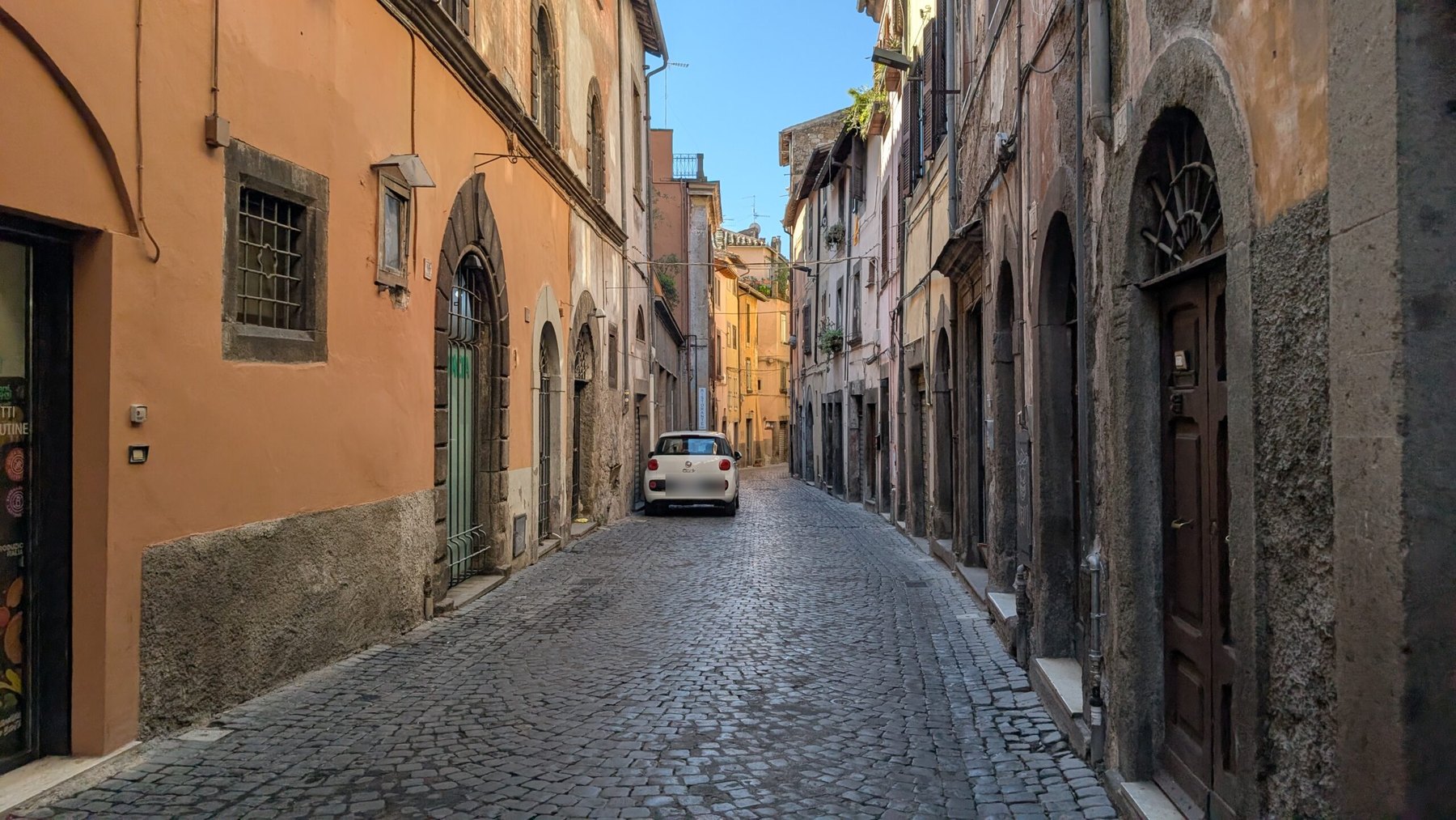 Una via lastricata del centro storico di Viterbo, tra facciate in peperino e portoni ad arco