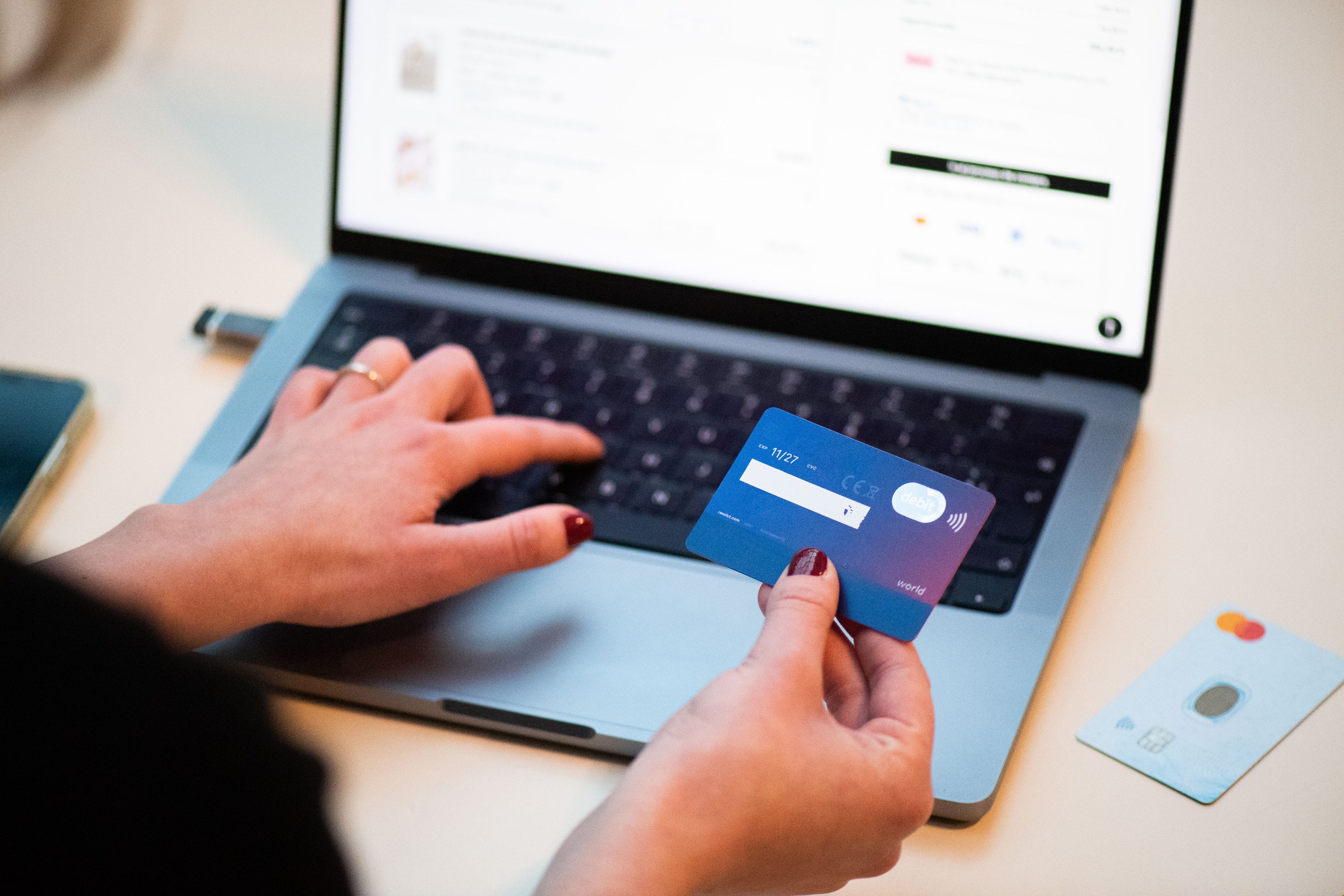 Mani che tengono una carta di pagamento davanti a un computer portatile aperto su un negozio online