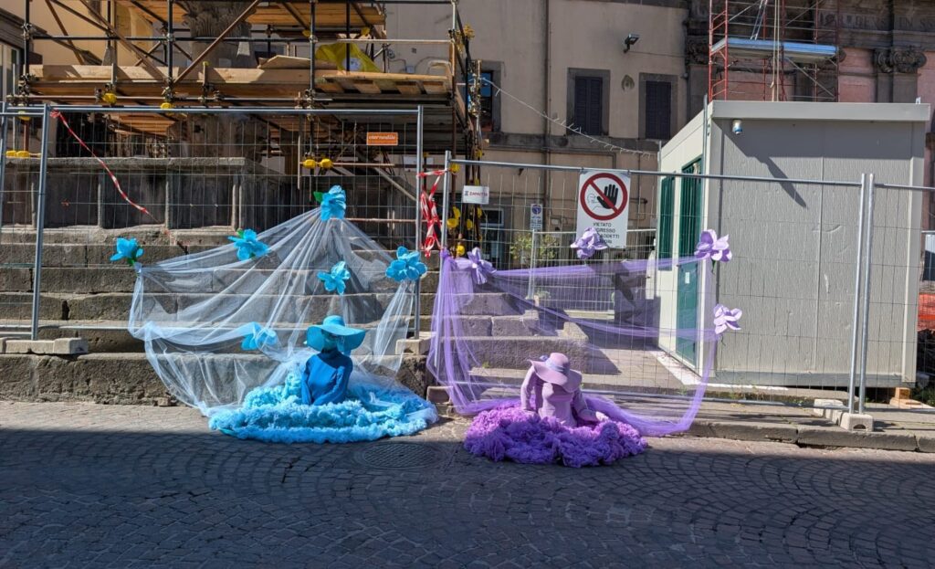 Due manichini vestiti di tulle davanti a un cantiere recintato
