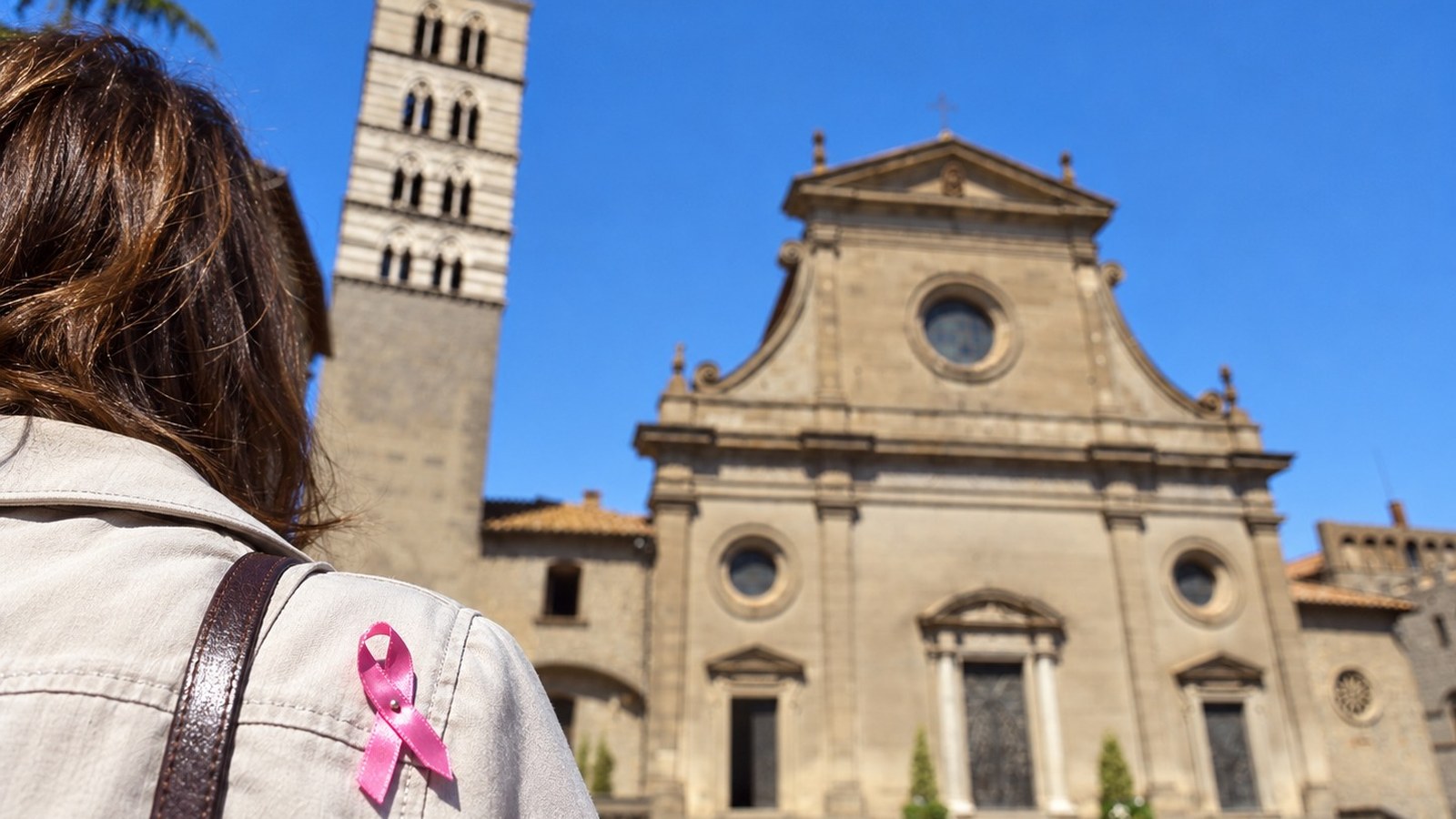 Fiocco rosa di Ottobre Rosa sulla giacca di una persona di spalle, davanti al Duomo di San Lorenzo a Viterbo