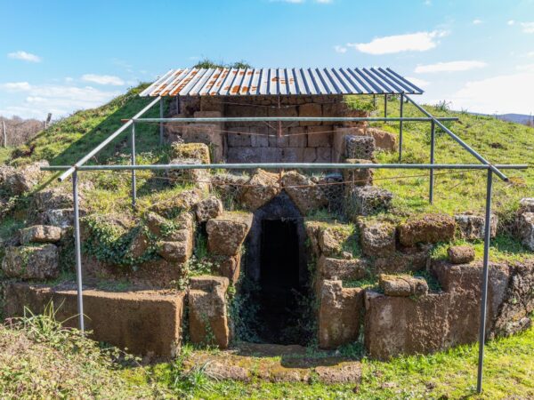 Tomba a tumulo etrusca con una tettoia di lamiera arrugginita su pali di metallo nella necropoli di San Giovenale