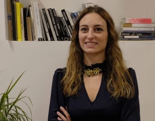 La psicologa e psicoterapeuta Silvia Trotto, in piedi a braccia conserte davanti a una libreria